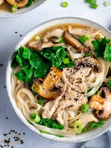 Bowl of chicken noodle soup with kale and mushrooms