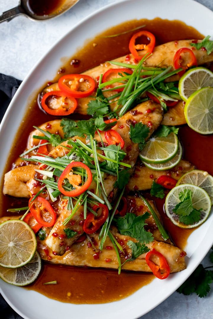 Baked Asian-style sea bass fillets on a white plate