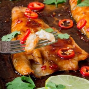 Asian-style sea bass fillets on a baking tray with spring onions and chillies