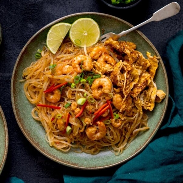 Square image of Mee Siam fried noodles on a green plate on a dark background.