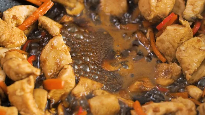 Chicken with Asian-style sauce bubbling in a wok