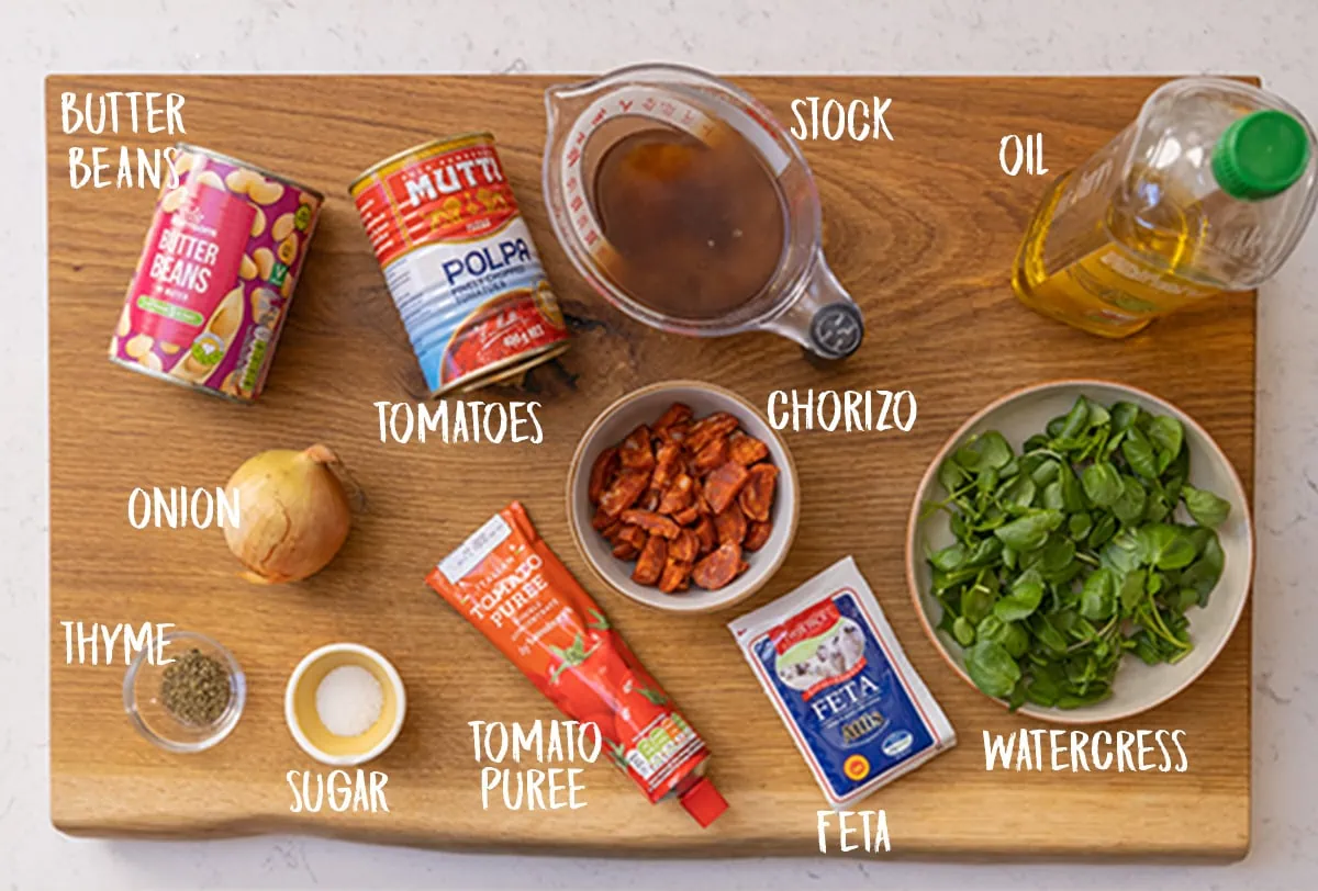 Ingredients for butterbean and chorizo soup on a wooden board.