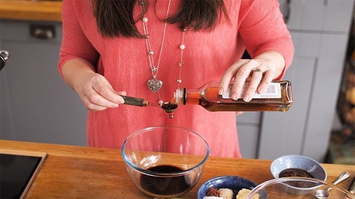 Pouring sesame oil in a bowl of marinade for kung pao chicken