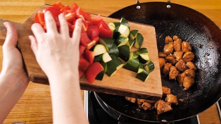 Adding veggies to wok for kung pao chicken