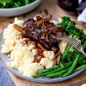 Slow cooker short ribs with gravy served on mashed potatoes with green veg