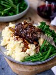 Slow cooker short ribs with gravy served on mashed potatoes with green beans
