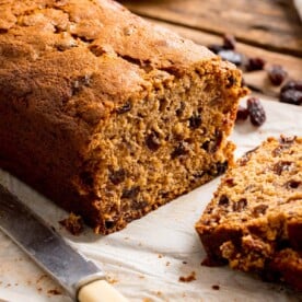 Close up of a fruit tea loaf that has been sliced on a wooden table.