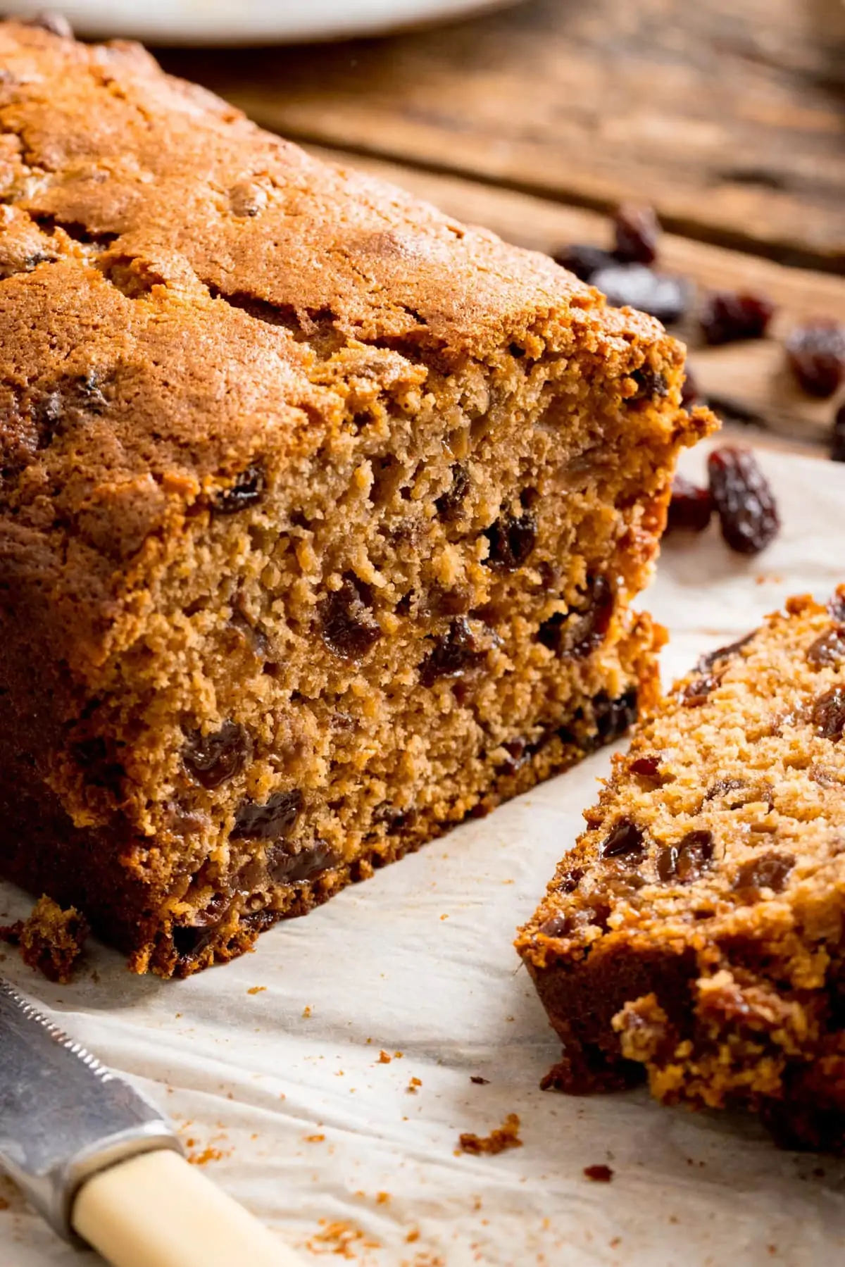 fruit tea loaf that has been sliced open on a wooden table.