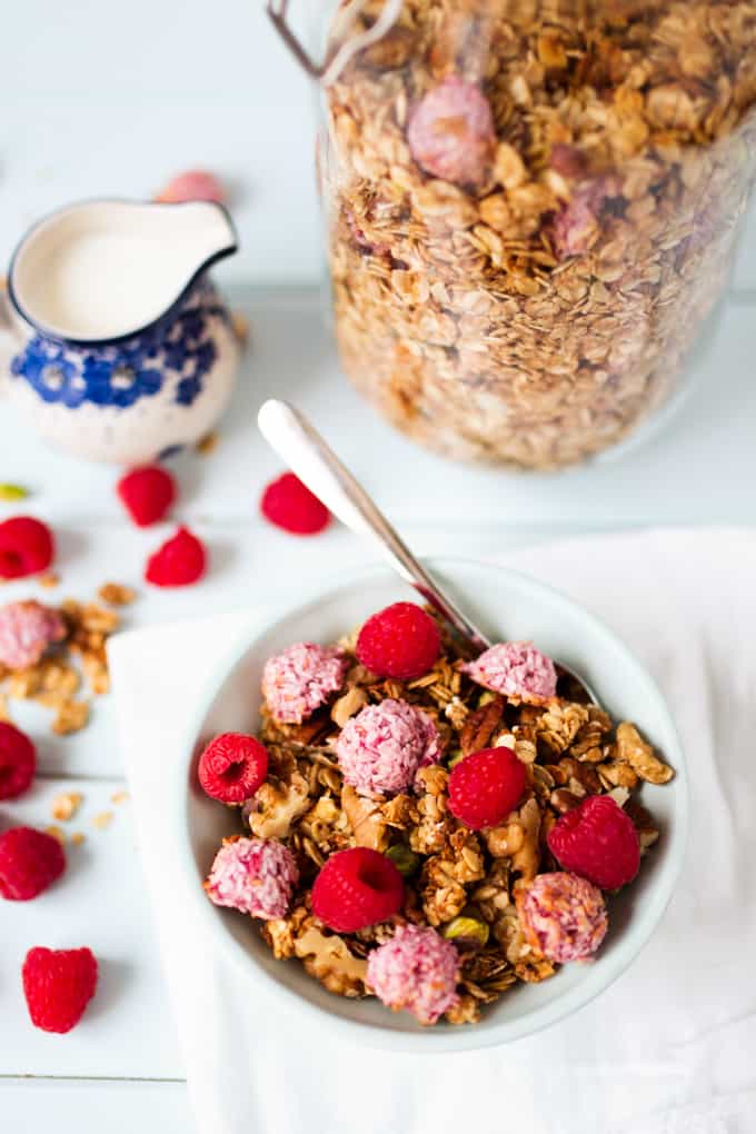 Bowl full of coconut oil granola topped with super-quick, fresh raspberry macaroons.