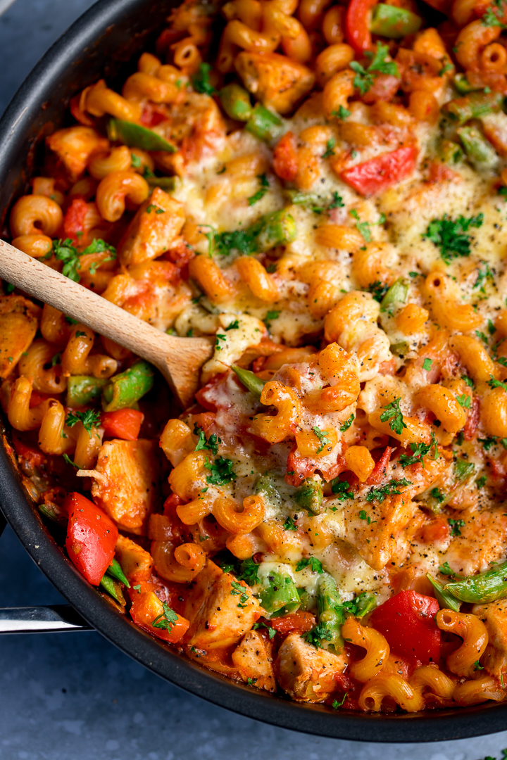 Close up of one pot chicken pasta with a wooden spoon in the pan