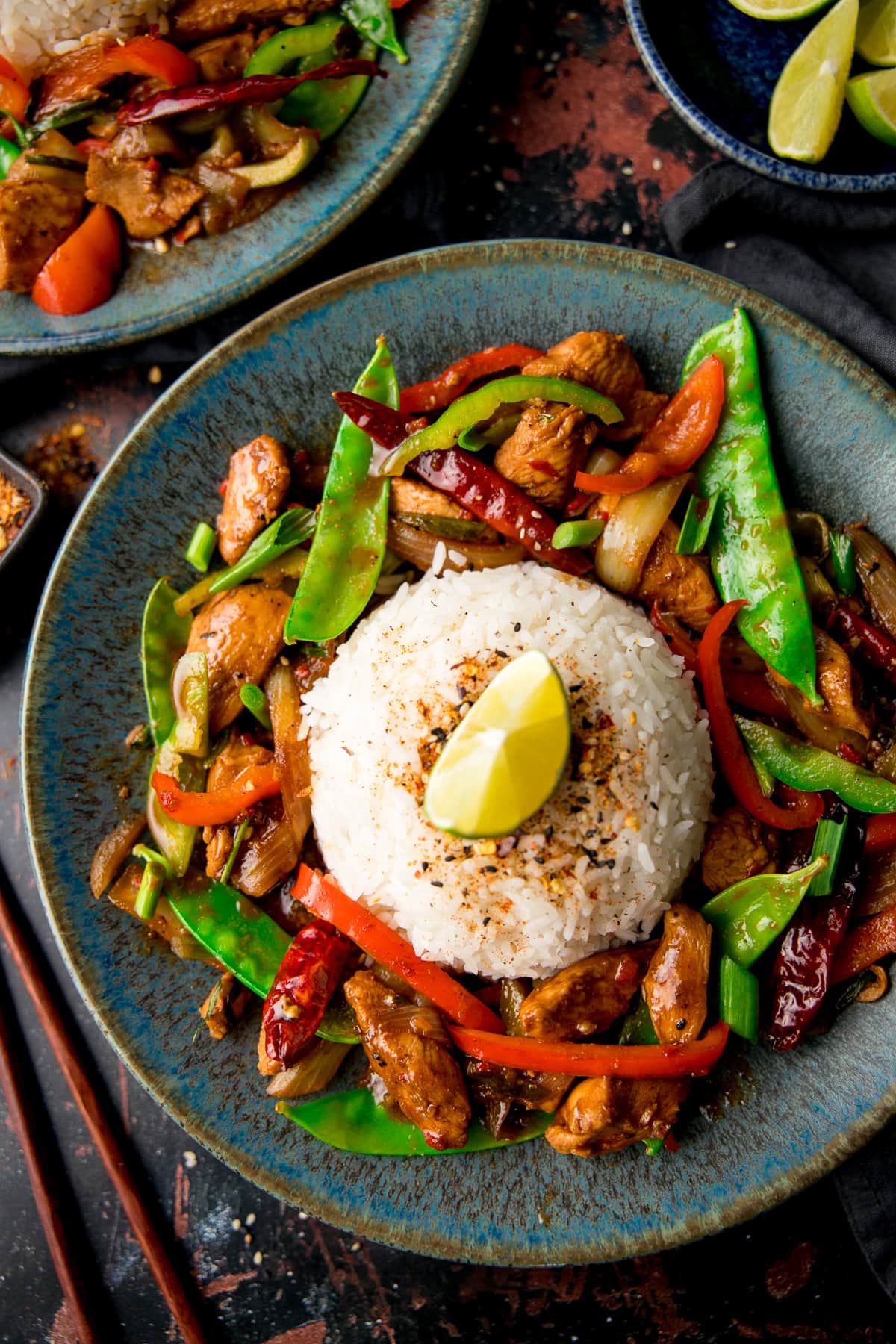 Firecracker chicken stir fry surrounding a mound of rice on a blue plate