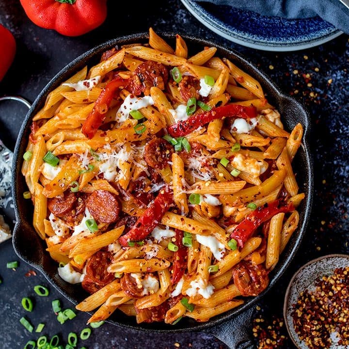 Overhead of penne arrabiata pasta in a pan on dark background