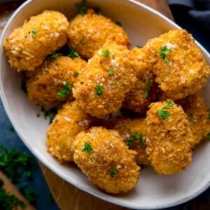 Close up image of potato croquettes in a white bowl sprinkled with parsely