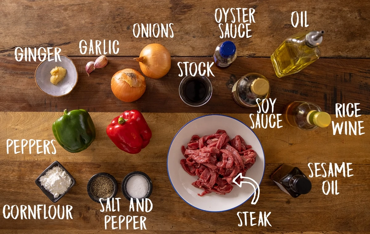 Ingredients for black pepper beef stir fry on a wooden table.