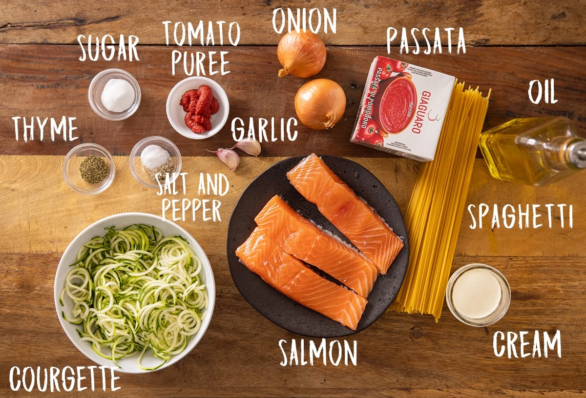 Ingredients for creamy tomato salmon and pasta on a wooden table