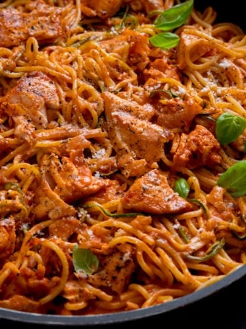 Spaghetti and pieces of salmon on a creamy tomato sauce in a pan
