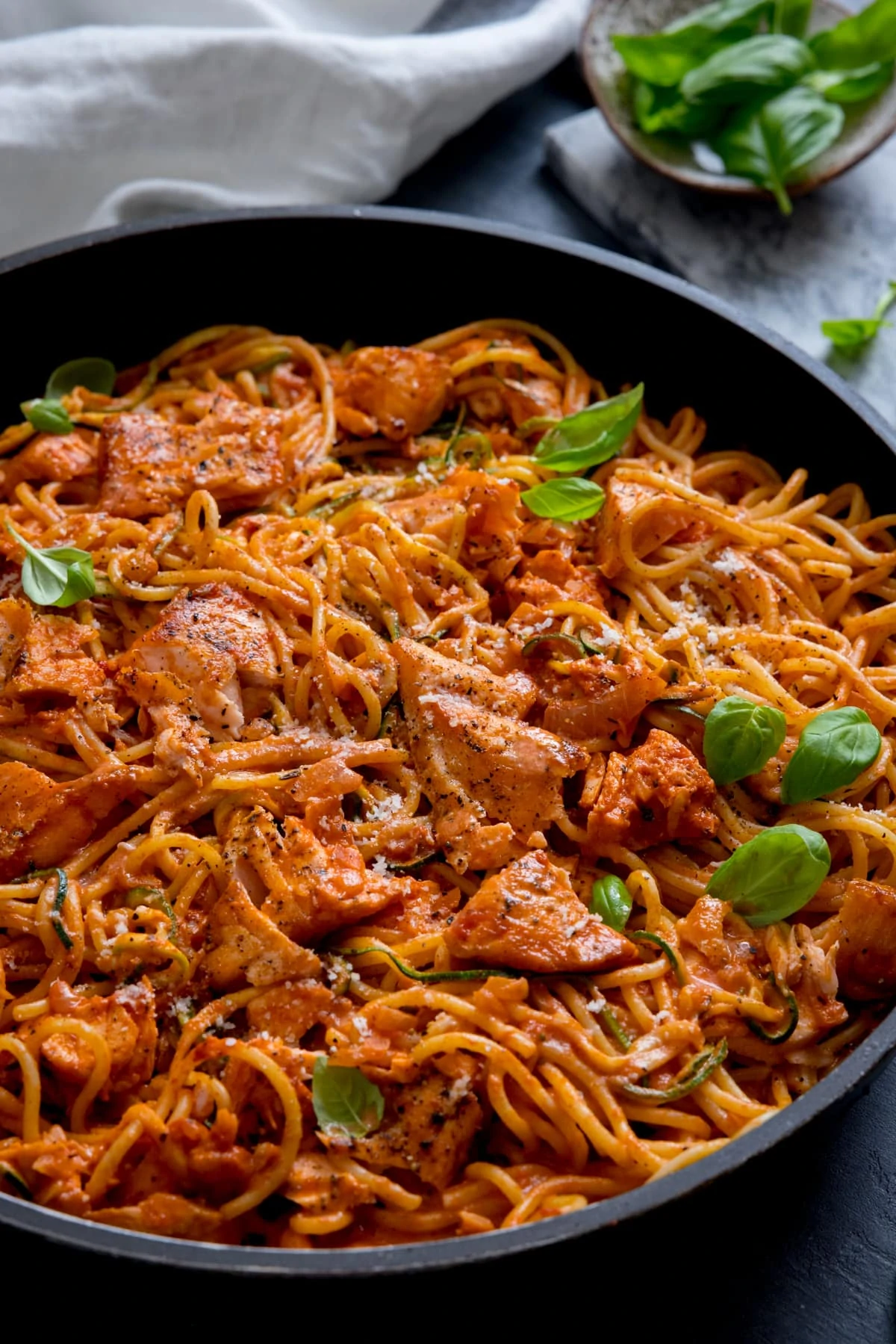 Creamy tomato spaghetti and salmon in a dark pan.