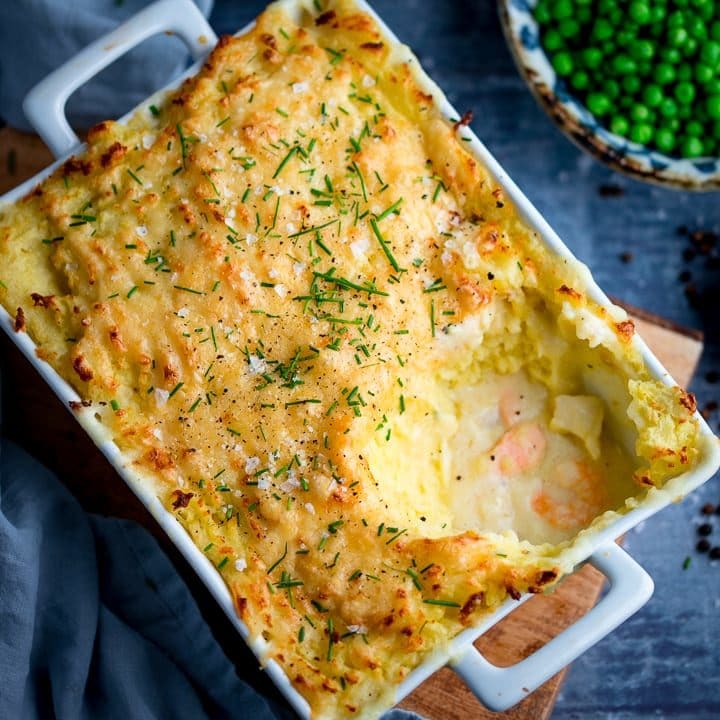 Fish pie with mashed potato in a white rectangular dish - scoop taken out