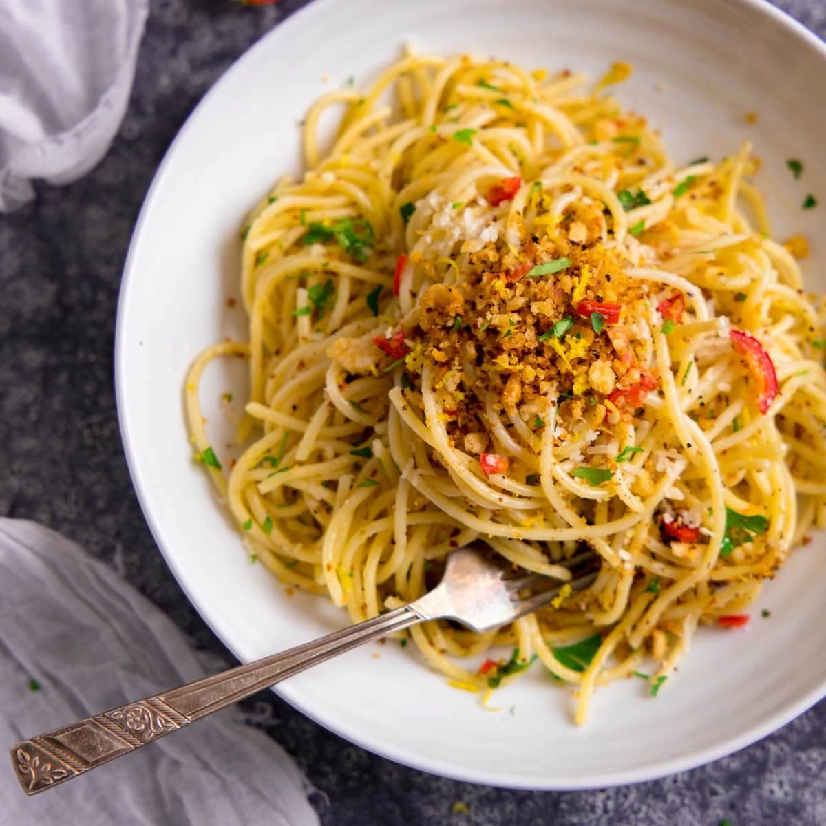 Spaghetti with garlic breadcrumbs and red chilli on a white plate.