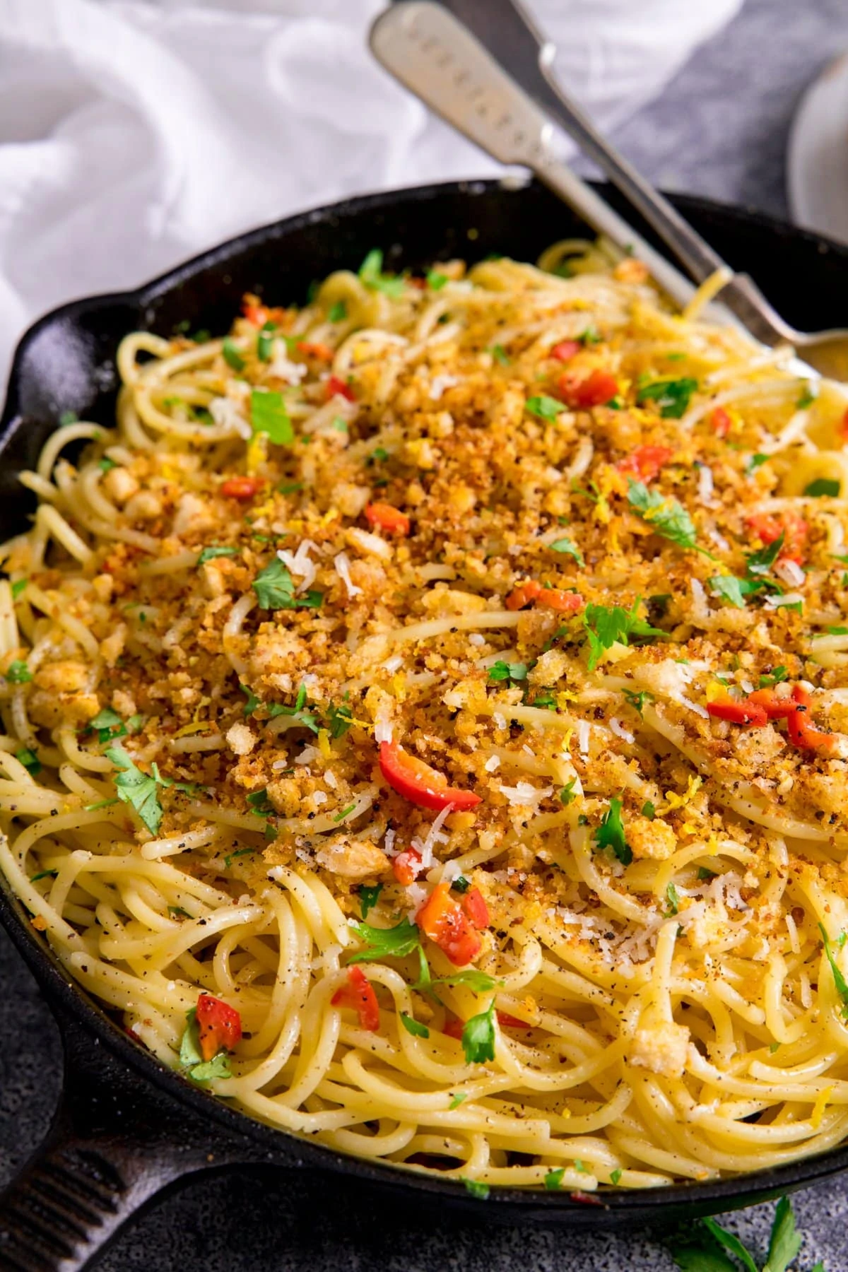 Black pan filled with spaghetti this is mixed with garlic breadcrumbs, chilli and parmesan.