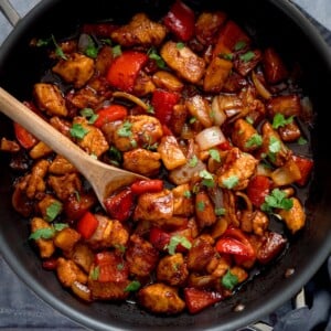 Overhead image of Sticky Pineapple Chicken Stir Fry in a pan. There is a wooden spoon sticking out of the pan.