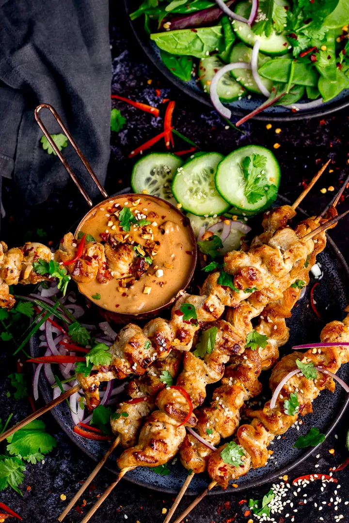 Chicken skewers with peanut satay sauce in a small pan on a dark background
