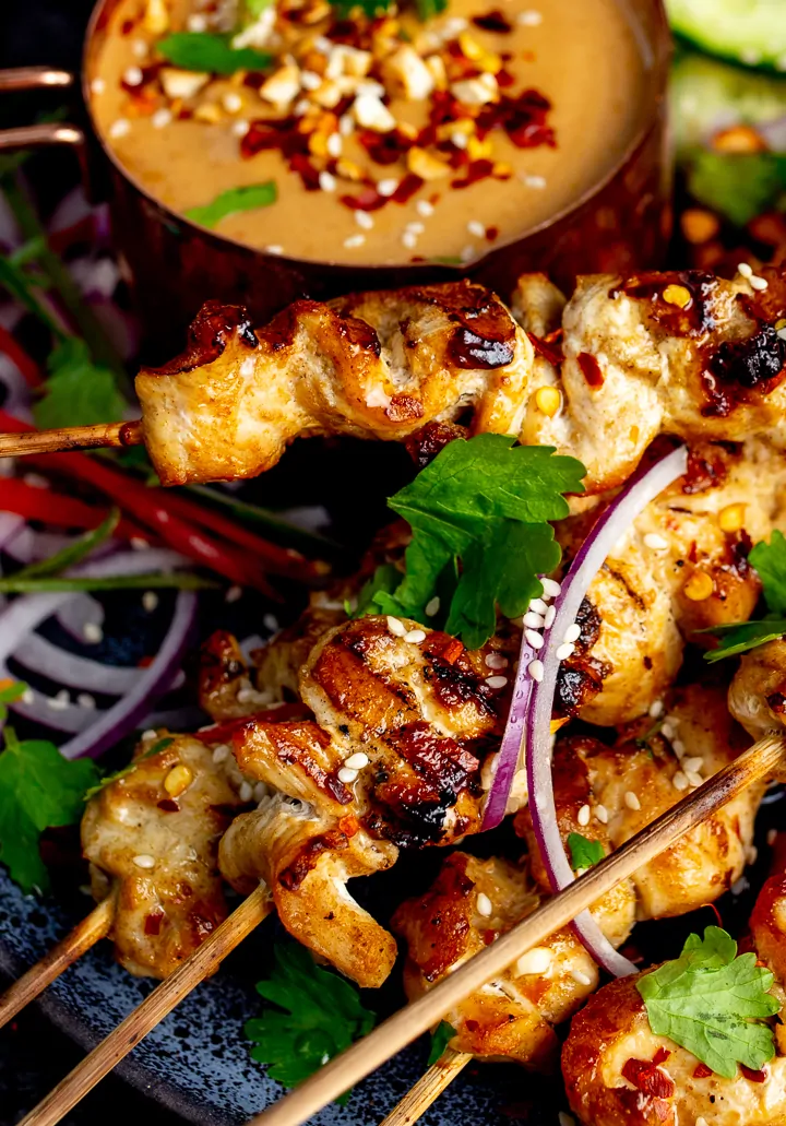 Close up of Thai chicken satay skewers on a dark background