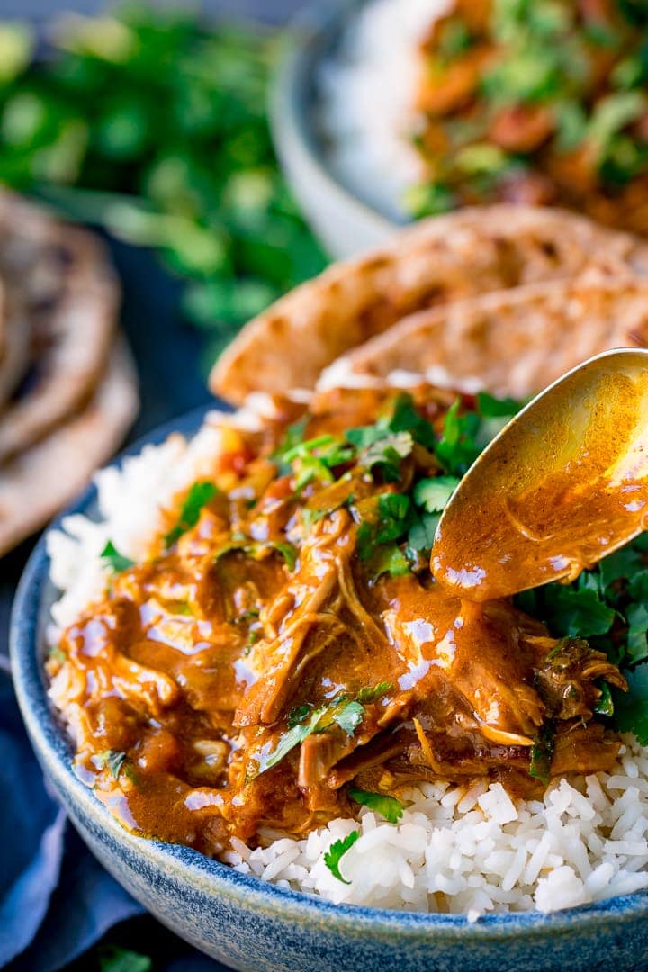 Slow cooked lamb curry being spooned over a bowl of rice