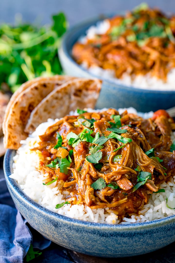 Slow cooked lamb curry in a blue bowl with rice.