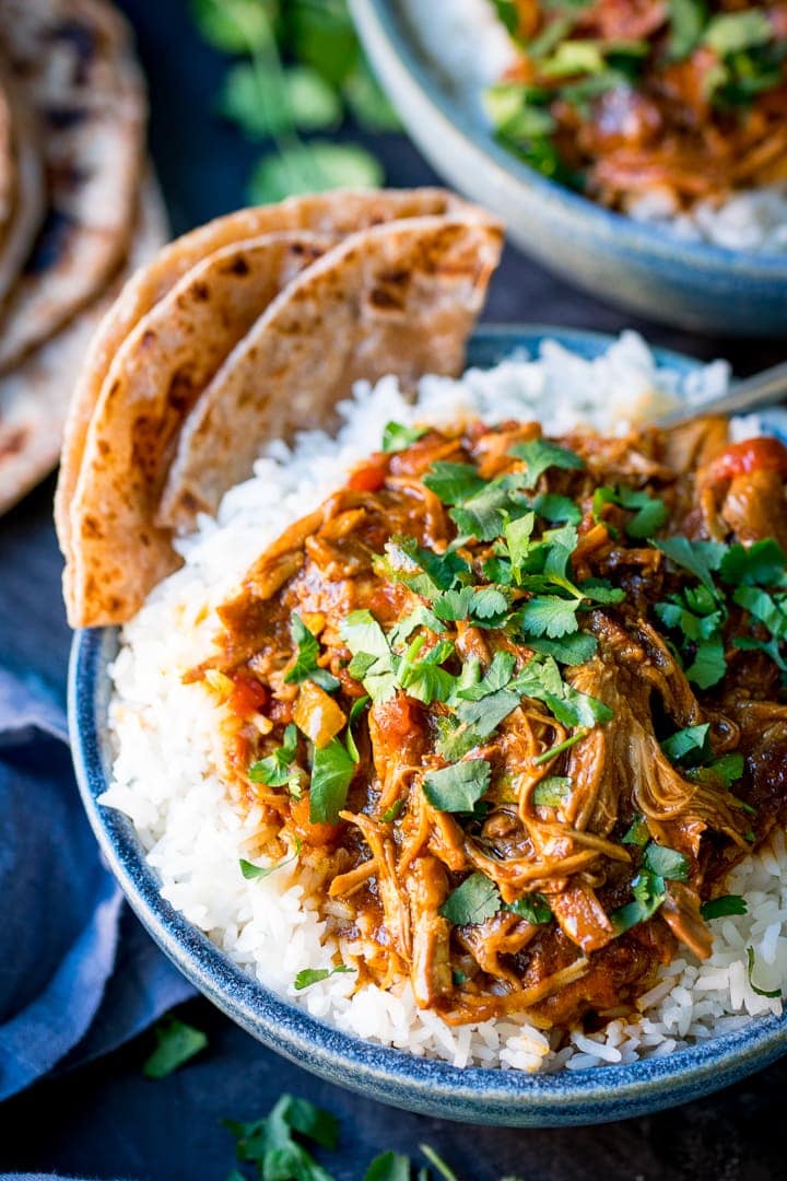 Slow cooked lamb curry on top of white rice in a blue bowl