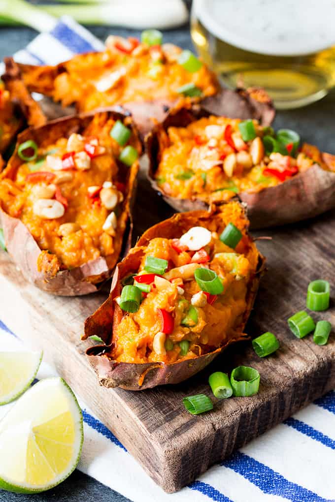 Thai-inspired sweet potato skins on a wooden board, topped with spring onions, chillies and peanuts.