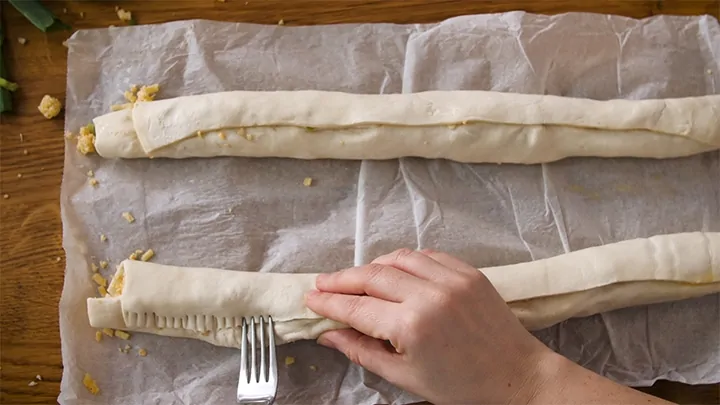 Sealing the pastry seams with a fork for vegetarian sausage rolls