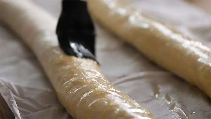 Brushing vegetarian sausage roll with egg wash before placing in oven.