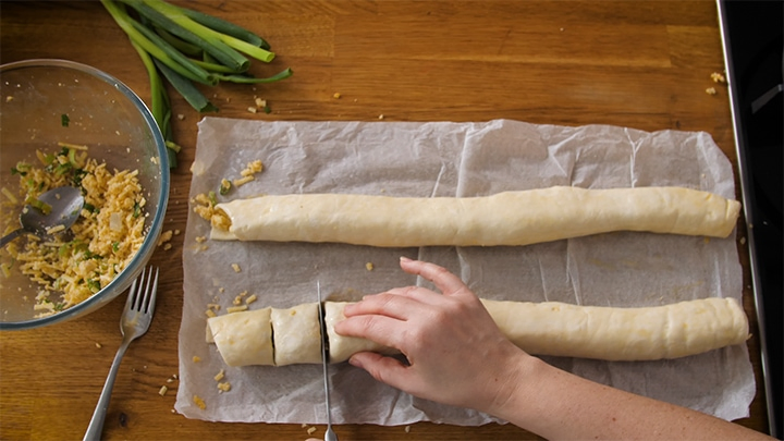 Slicing vegetarian sausage rolls into small sausage rolls before placing in oven.