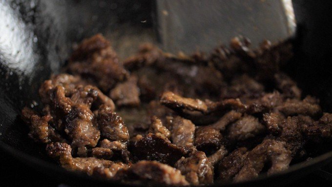 Strips of beef being fried for crispy orange beef dish