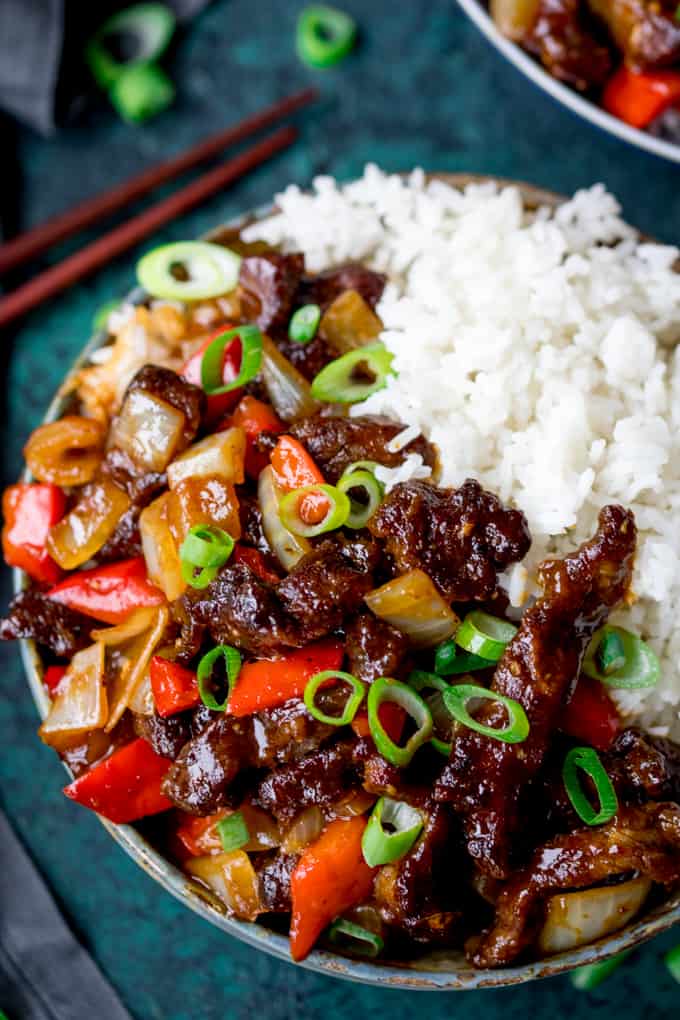 Overhead shot of crispy orange beef with onions and peppers in a bowl with rice
