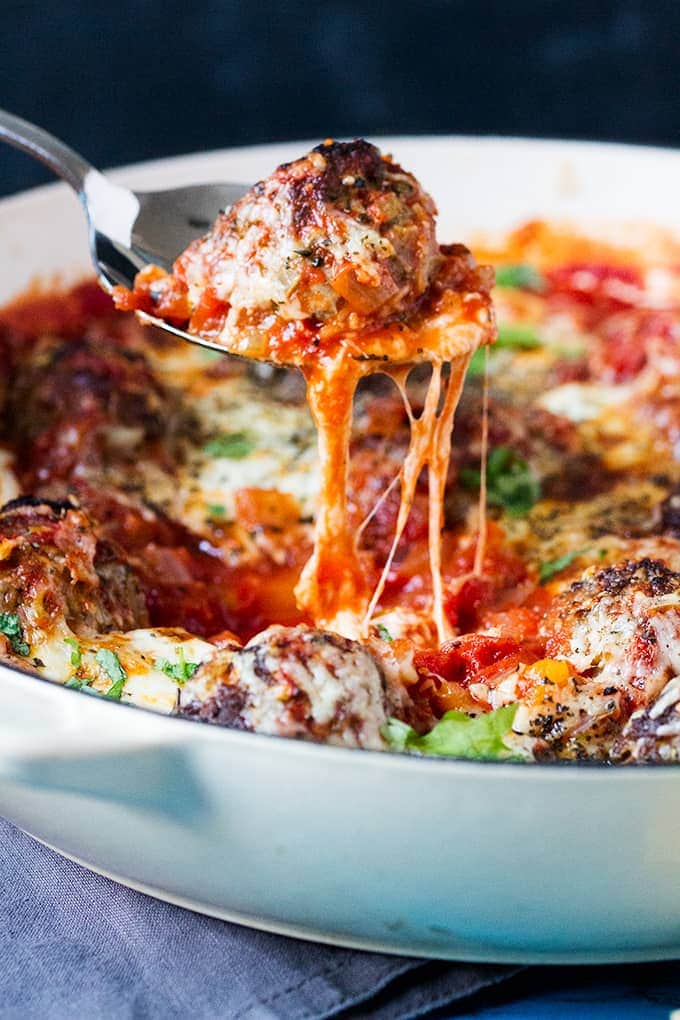 a meatball with hidden veg, served in a tomato and pepper sauce with gooey melted cheese being lifted on a spoon from a pan
