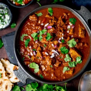 Slow-cooked spicy beef curry in a dish on a dark background