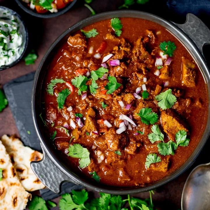 Slow-cooked spicy beef curry in a dish on a dark background