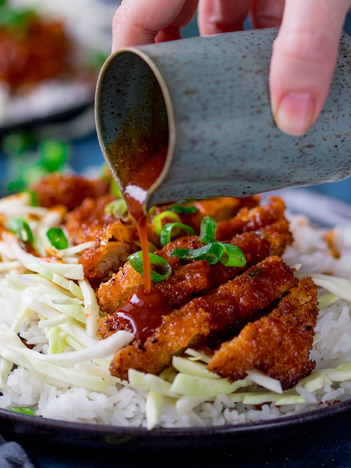 Tonkatsu curry sauce being poured onto pork katsu