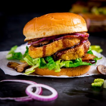 halloumi burger with lettuce and onions on a piece of parchment paper on a dark background