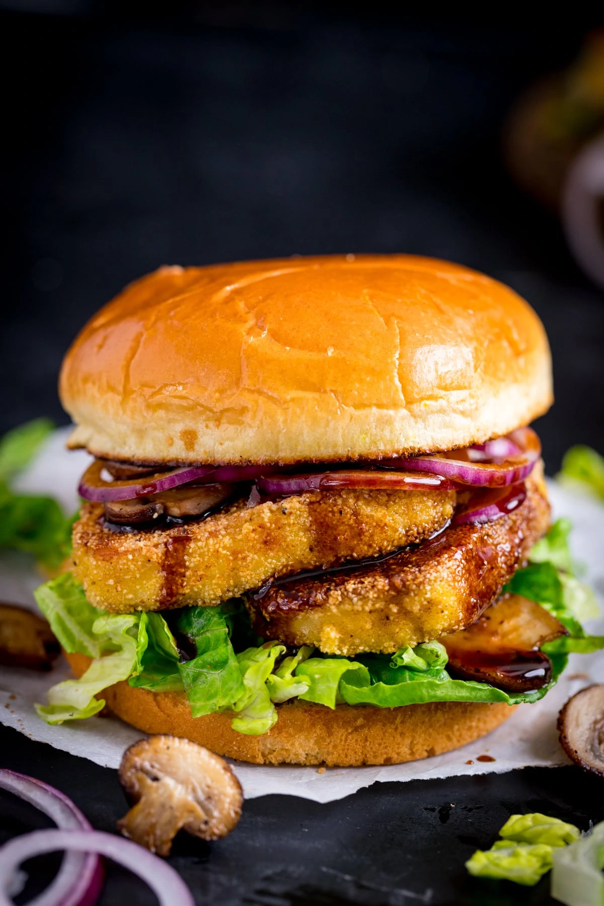 halloumi burger with lettuce, onions and mushrooms against a dark background.