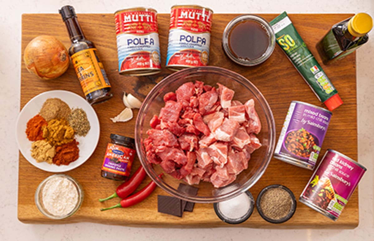 Ingredients for slow cooker pork and beef chilli on a wooden board.