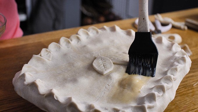 brushing the top of a chicken pie with egg wash