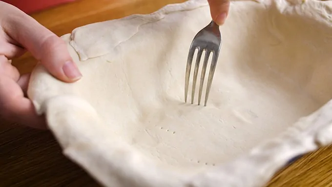 pricking the pastry base for chicken pie