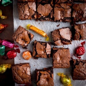 Overhead picture of some chocolate brownies on baking parchment with chocolates from the chocolate box scattered around.