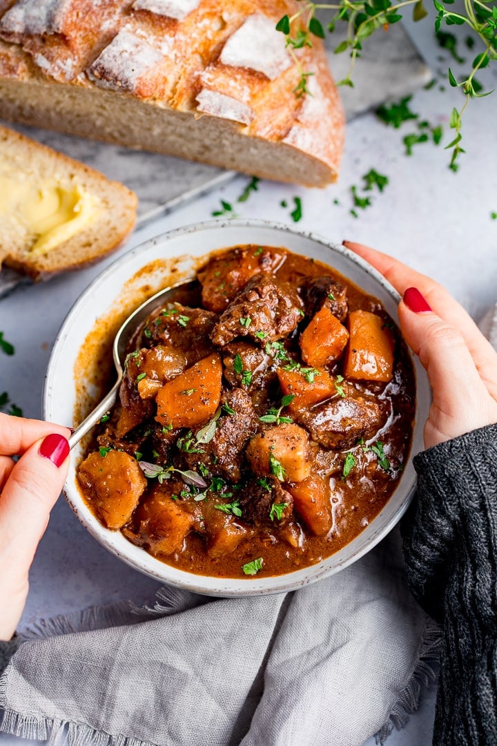 Hands around a bowl of Scottish beef stew. A spoonful being taken,