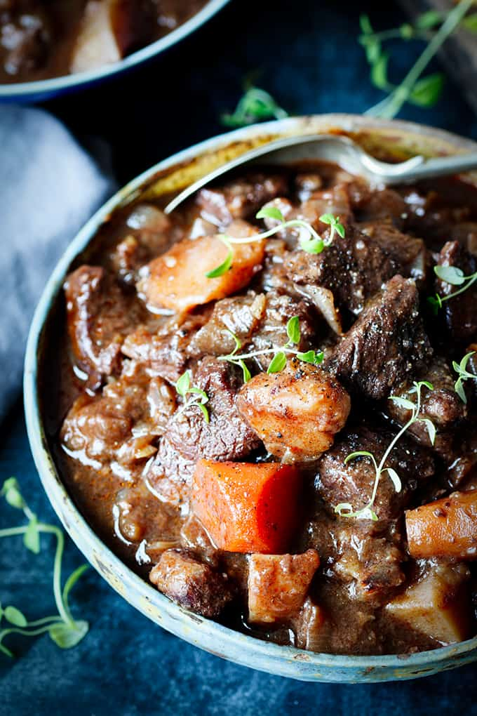 Hands around a bowl of Scottish beef stew. A spoonful being taken,