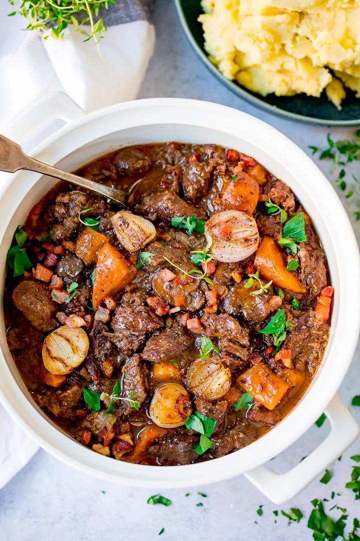 Overhead image of beef bourguignon in a pan on a light background