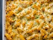 Overhead image of tuna pasta bake in a white dish topped with finely chopped parsley.